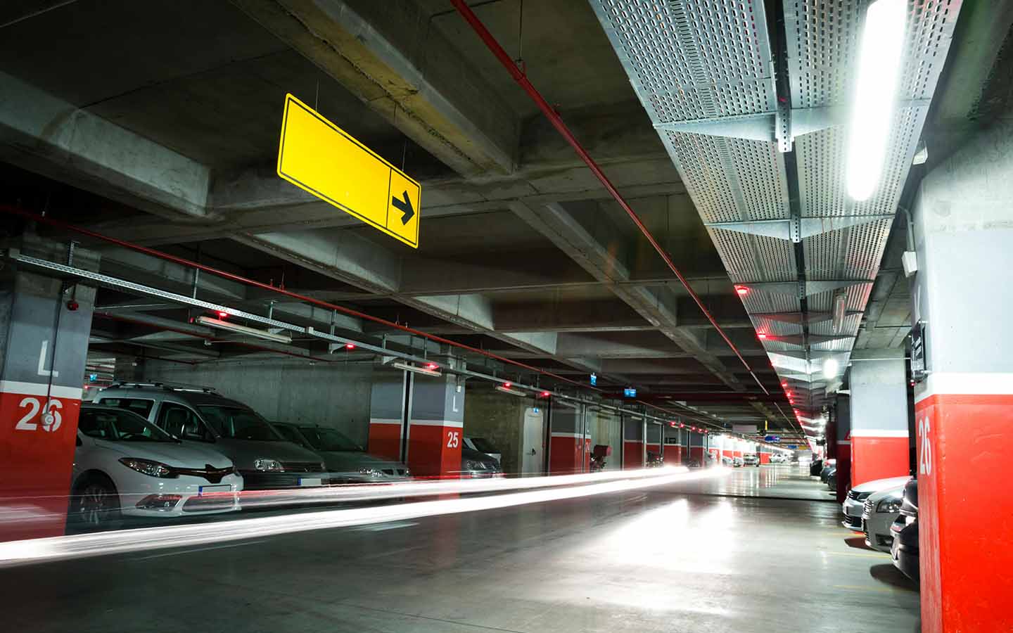 Underground parking garage with vehicle light trails and illuminated directional signs